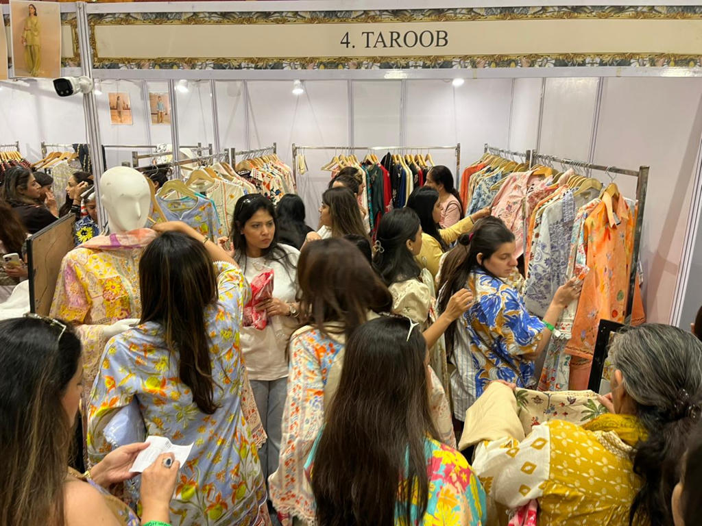 Shoppers browsing clothing racks at the Taroob exhibition booth during a fashion pop-up event